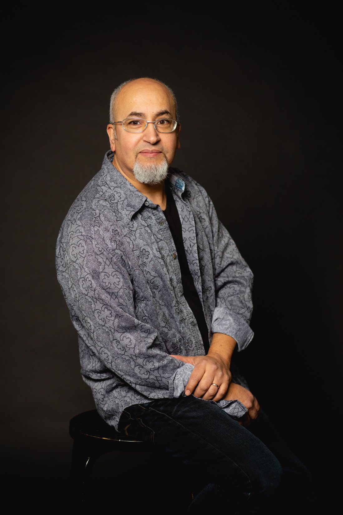 Said Yaaqoubi, seated, wearing glasses and a grey patterned shirt